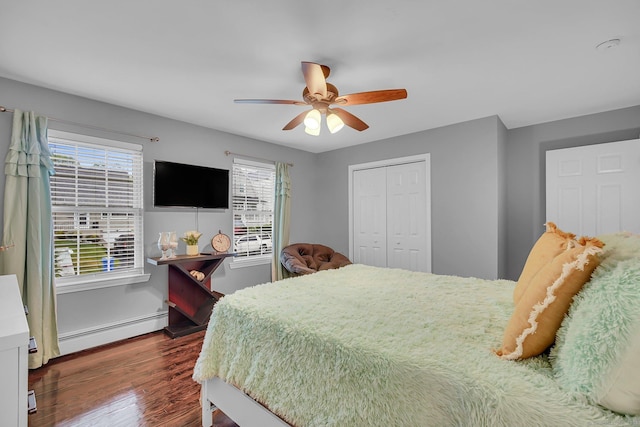 bedroom with baseboard heating, dark wood-style floors, a closet, and a ceiling fan