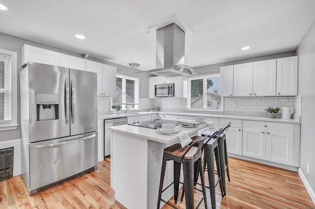 84 Oxford St, Bridgeport, CT 06606 - kitchen featuring stainless steel appliances, island exhaust hood, a breakfast bar area, white cabinetry, and light countertops