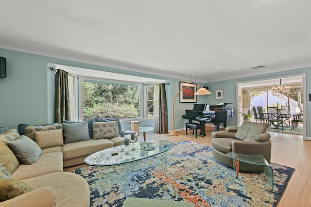 living area with visible vents, crown molding, wood finished floors, baseboards, and a chandelier
