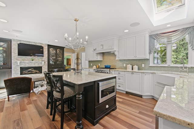 kitchen with appliances with stainless steel finishes, white cabinets, light stone countertops, and a notable chandelier