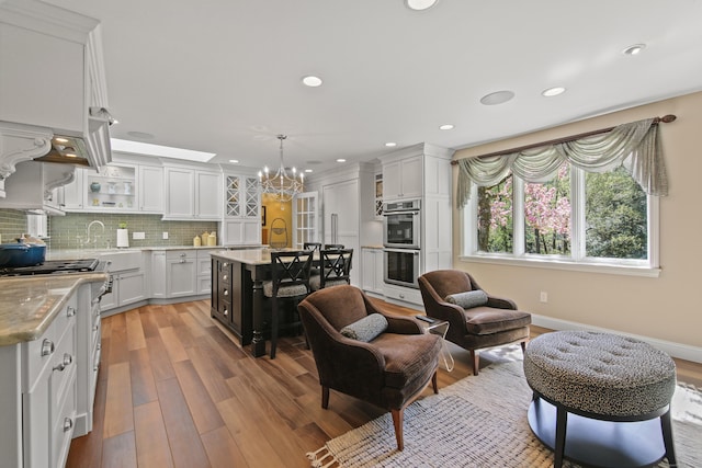 kitchen with stainless steel double oven, a chandelier, white cabinetry, recessed lighting, and wood finished floors