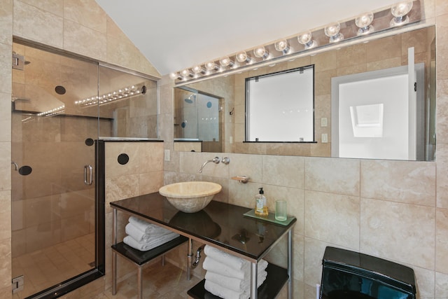 full bath with tile walls, a sink, lofted ceiling, and a stall shower
