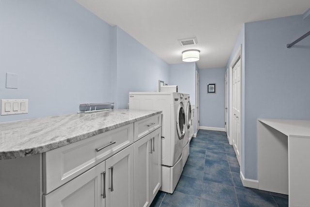 washroom featuring visible vents, washer and dryer, baseboards, dark tile patterned flooring, and cabinet space
