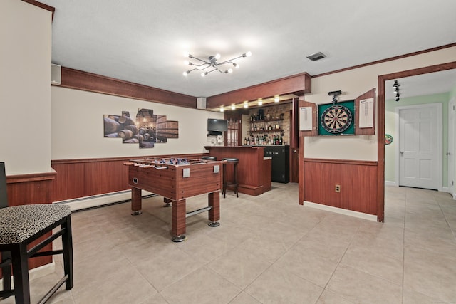 game room with a bar, wainscoting, a baseboard heating unit, and wooden walls