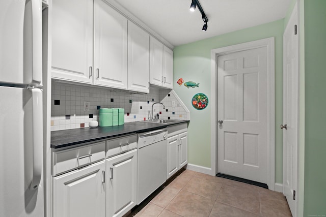 kitchen with decorative backsplash, dark countertops, white appliances, white cabinetry, and a sink