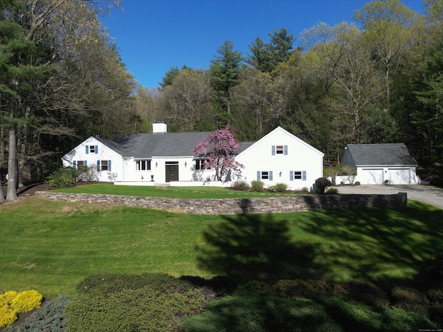 single story home featuring a detached garage, a chimney, an outdoor structure, and a front lawn
