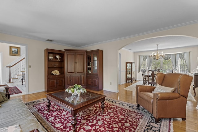 living area featuring visible vents, ornamental molding, stairs, arched walkways, and a notable chandelier