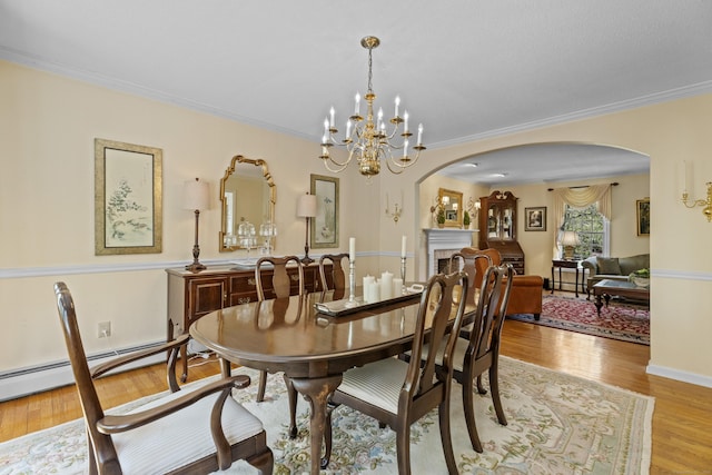 dining space with crown molding, arched walkways, a chandelier, and wood finished floors