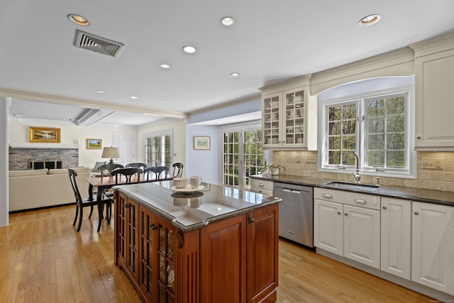 kitchen with visible vents, a healthy amount of sunlight, a fireplace, a sink, and dishwasher