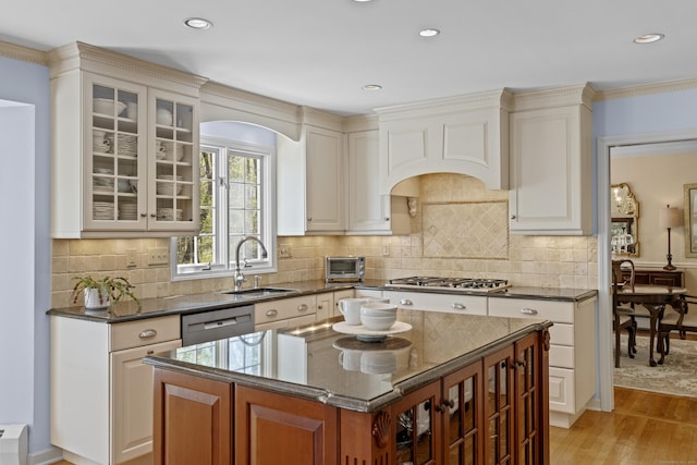 kitchen featuring a sink, appliances with stainless steel finishes, light wood-style floors, and glass insert cabinets
