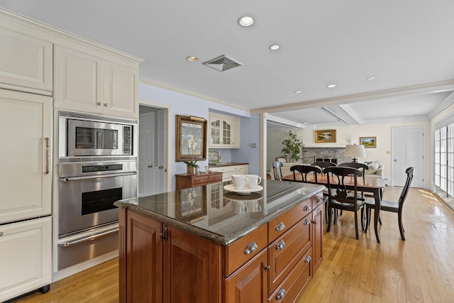 kitchen featuring visible vents, a fireplace, light wood-style floors, a warming drawer, and stainless steel appliances