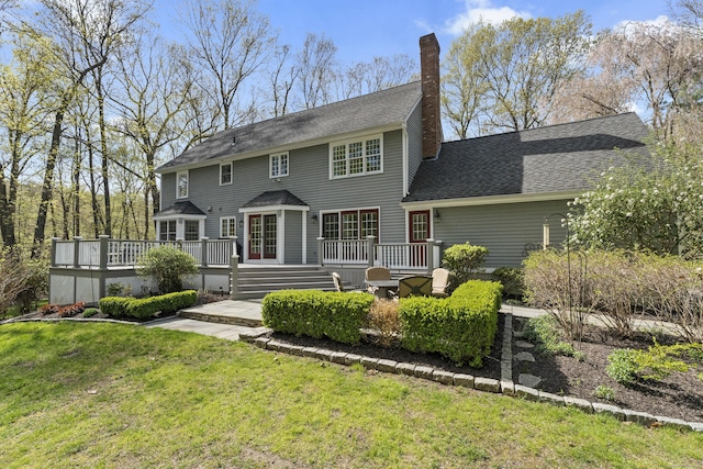 back of property featuring roof with shingles, a yard, a chimney, and a deck