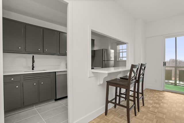 kitchen featuring light countertops, a sink, a breakfast bar area, and stainless steel appliances