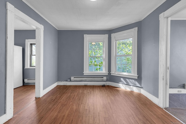 unfurnished room with crown molding, baseboards, wood finished floors, and baseboard heating