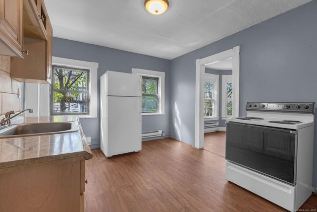 kitchen with freestanding refrigerator, a sink, wood finished floors, baseboard heating, and electric stove