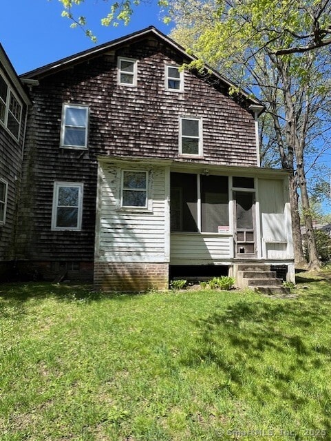 back of property featuring a lawn and a sunroom