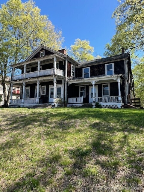 view of front of home featuring a porch, a front lawn, and a chimney