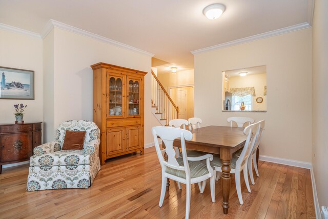 dining area featuring light wood-style floors, stairs, ornamental molding, and baseboards