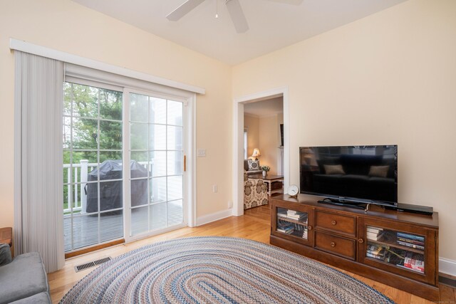 living area with ceiling fan, light wood finished floors, and baseboards