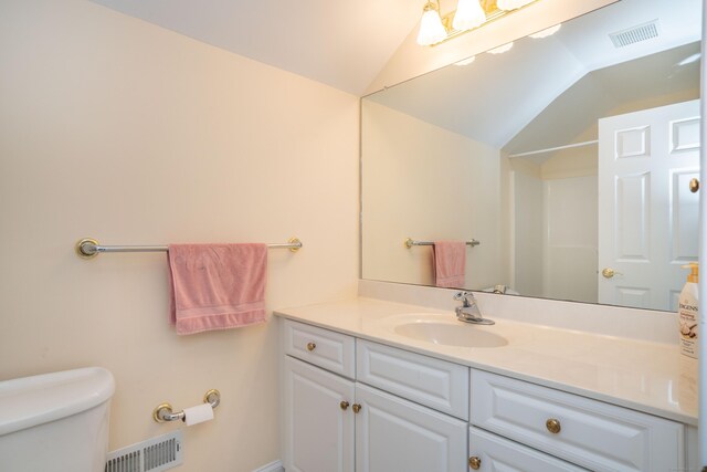 bathroom featuring lofted ceiling, toilet, and vanity