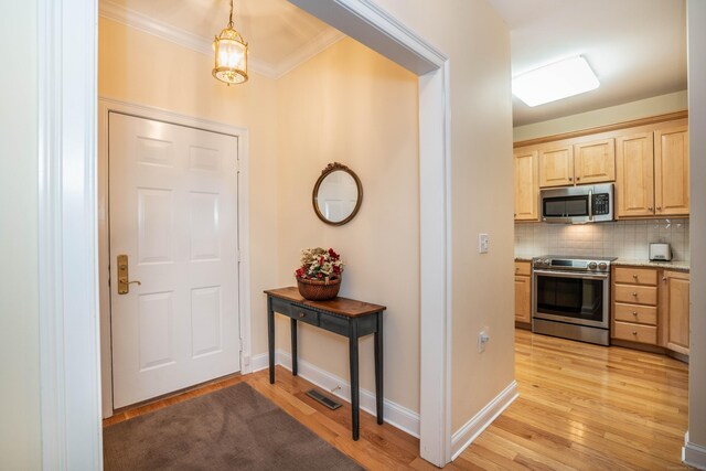 entryway featuring light wood-type flooring, ornamental molding, baseboards, and a chandelier