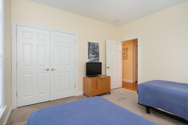 carpeted bedroom with a closet and baseboards