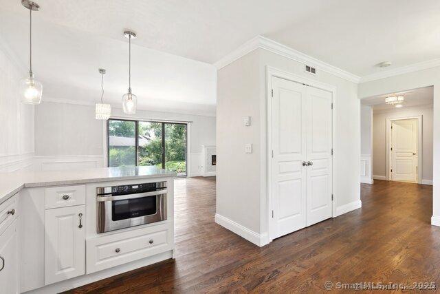 kitchen with dark wood-style flooring, oven, white cabinets, and a peninsula