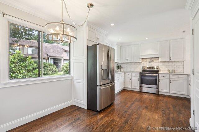 122 Heritage Vlg Unit B, Southbury, CT 06488 - kitchen featuring appliances with stainless steel finishes, a chandelier, light countertops, dark wood finished floors, and white cabinetry