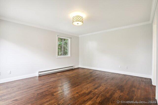 unfurnished room featuring baseboards, a baseboard heating unit, ornamental molding, and wood finished floors