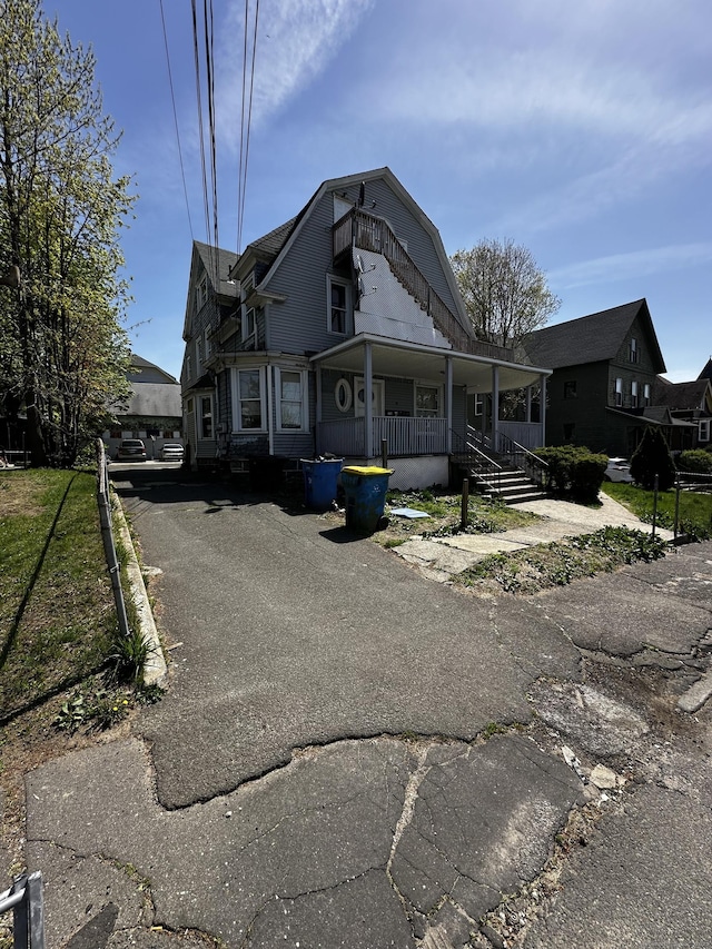 view of front facade with covered porch and a gambrel roof
