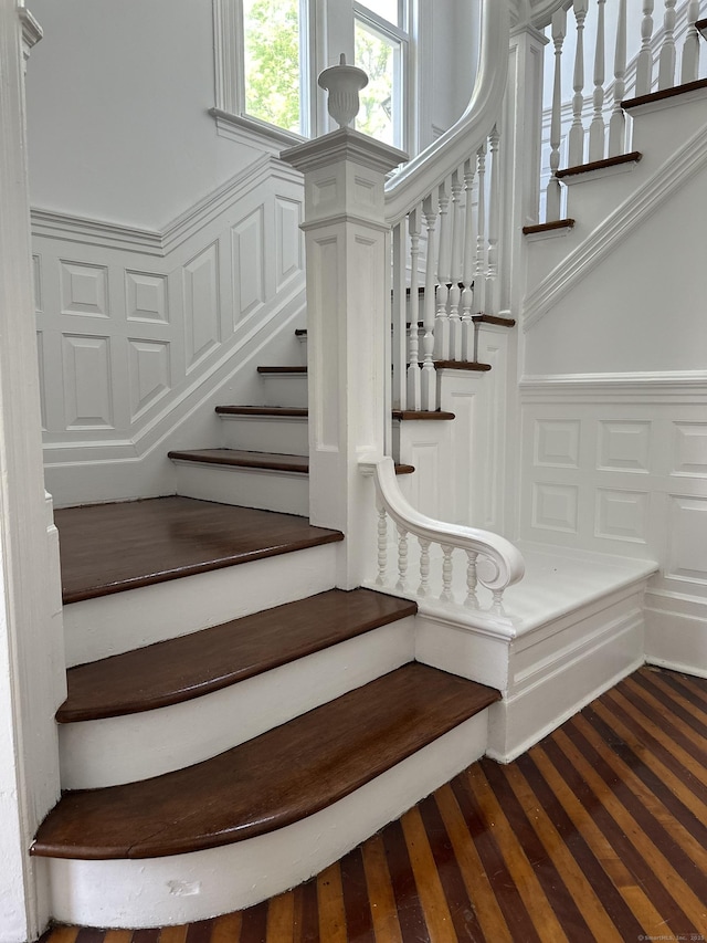 staircase featuring a wainscoted wall and a decorative wall