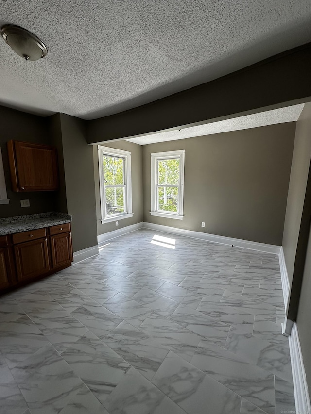 interior space with baseboards, a textured ceiling, and marble finish floor