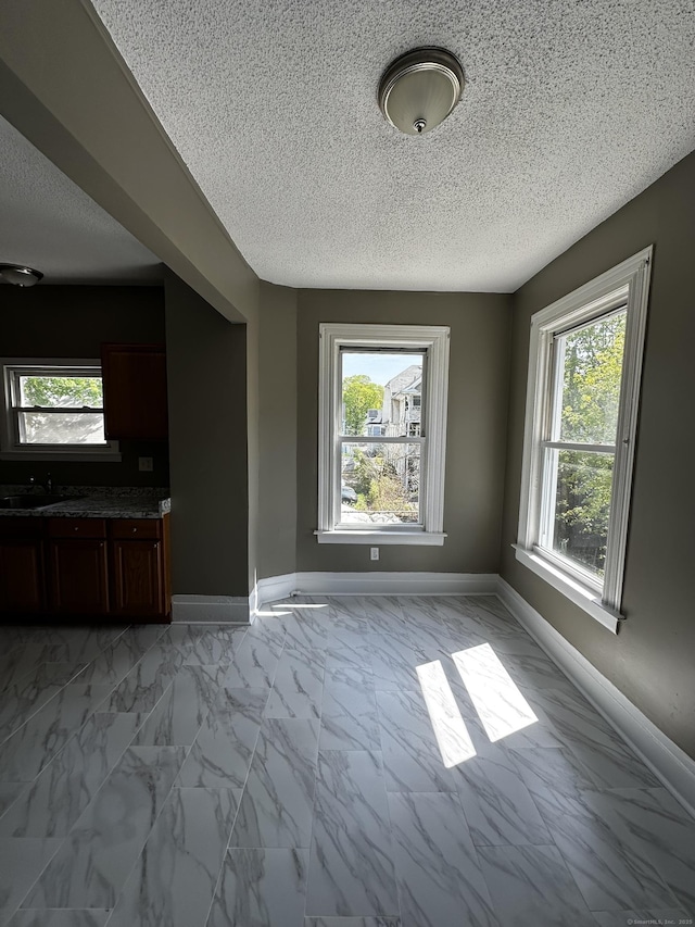 interior space with baseboards, a textured ceiling, and marble finish floor