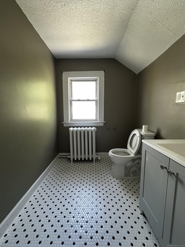 half bath featuring lofted ceiling, toilet, baseboards, radiator heating unit, and a textured ceiling