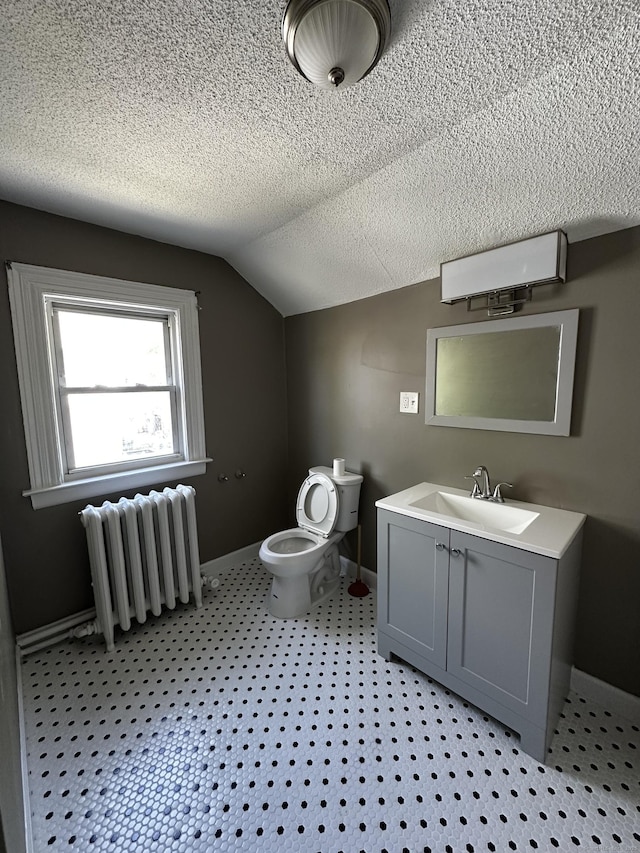 bathroom with vanity, toilet, radiator heating unit, baseboards, and lofted ceiling