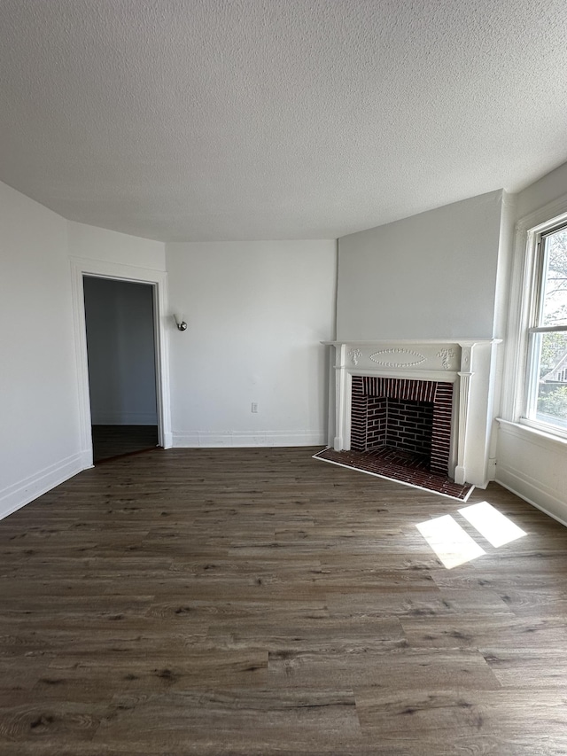 unfurnished living room with heating unit, dark wood finished floors, a textured ceiling, and a fireplace