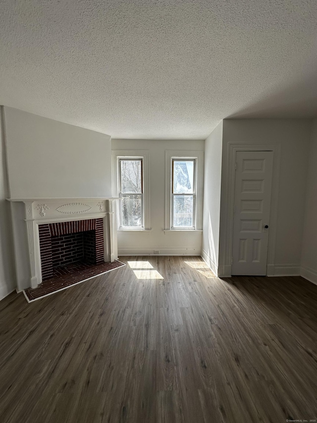 unfurnished living room featuring a textured ceiling, baseboards, and wood finished floors