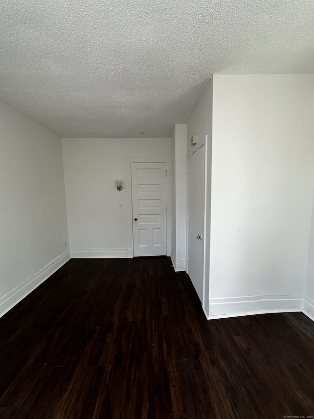 unfurnished room featuring baseboards, a textured ceiling, and wood finished floors