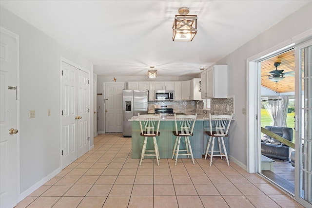 6 Margaret Cir, Pomfret, CT 06259 - kitchen featuring white cabinets, stainless steel appliances, light tile patterned flooring, and a peninsula