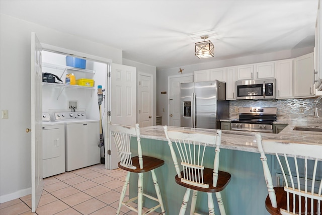 6 Margaret Cir, Pomfret, CT 06259 - kitchen with a peninsula, white cabinets, washing machine and clothes dryer, a sink, and stainless steel appliances