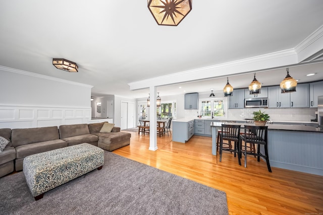 living room with crown molding, a decorative wall, and light wood finished floors