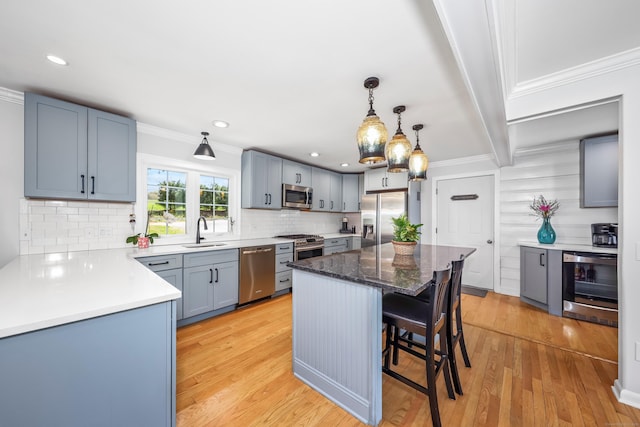 kitchen featuring crown molding, a kitchen breakfast bar, tasteful backsplash, a sink, and stainless steel appliances