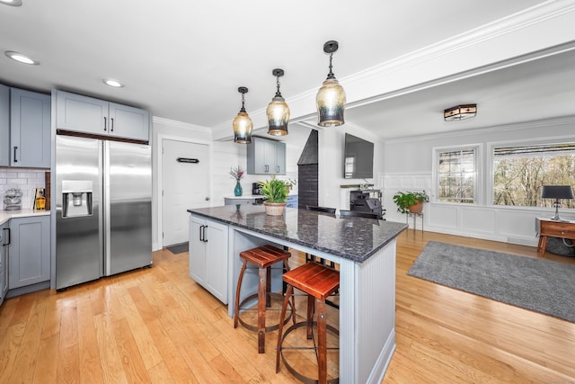 kitchen with stainless steel fridge, light wood finished floors, a breakfast bar area, and a kitchen island