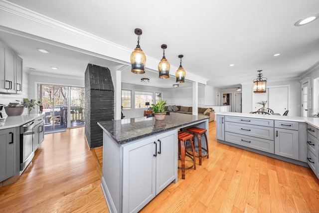 kitchen featuring gray cabinetry, a kitchen breakfast bar, open floor plan, and a healthy amount of sunlight