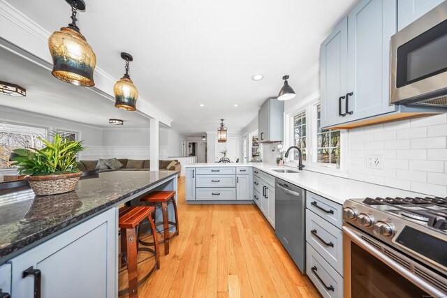kitchen with a peninsula, open floor plan, a breakfast bar area, a sink, and appliances with stainless steel finishes