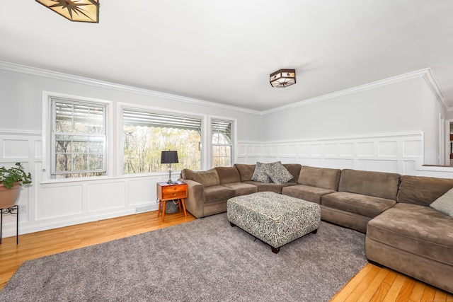 living area with ornamental molding, a decorative wall, and wood finished floors