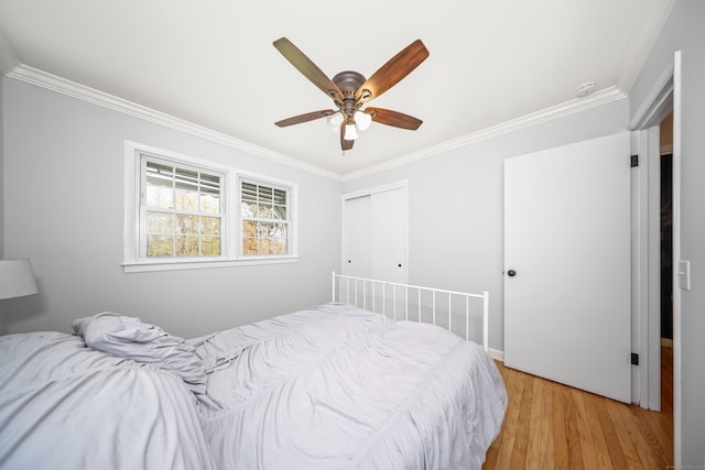 bedroom featuring crown molding, a closet, a ceiling fan, and light wood-style floors