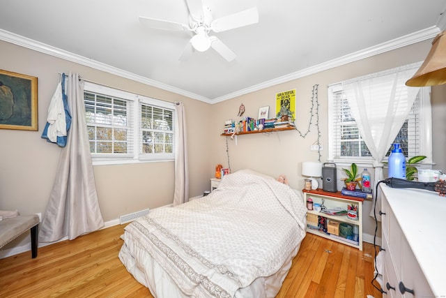 bedroom featuring crown molding, visible vents, multiple windows, and light wood finished floors