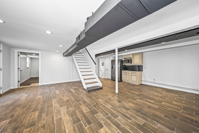 finished below grade area featuring dark wood-style flooring, stainless steel fridge, stairs, recessed lighting, and baseboards