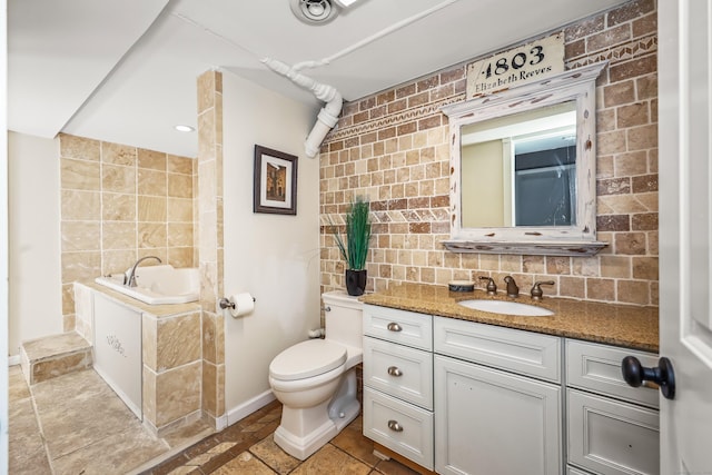 bathroom featuring vanity, toilet, baseboards, tasteful backsplash, and a garden tub